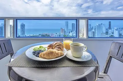 a table with a plate of food and a cup of coffee at Riviera Coral Beach - Con vista al mar in Cartagena de Indias