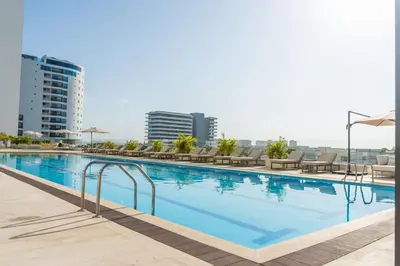a large swimming pool with chairs and umbrellas at Ocean View ApartaSuite 16th Floor in Cartagena de Indias
