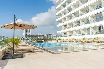 a swimming pool with chairs and an umbrella next to a building at Ocean View ApartaSuite 16th Floor in Cartagena de Indias