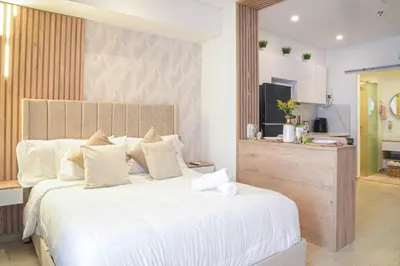a bedroom with a large white bed and a kitchen at Ocean View ApartaSuite 16th Floor in Cartagena de Indias
