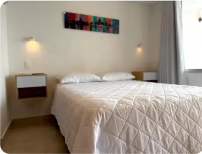 a bedroom with a white bed and a painting on the wall at Moderno Apto cerca del Mar y Aeropuerto in Cartagena de Indias