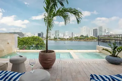 a pool with a palm tree next to a building at Hotel Casa Sonara in Cartagena de Indias