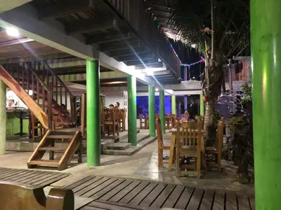 a restaurant with green columns and people sitting in chairs at eco hotel lili in Isla Fuerte