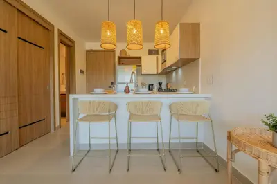a kitchen with a white counter and stools at BK2L | Escápate a Baía Kristal, sol + arena blanca in Los Arrayanes