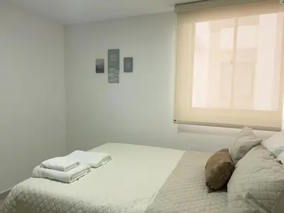 a white bedroom with a bed with towels on it at 2 cuartos AC y piscina in Cartagena de Indias