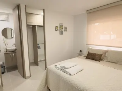 a white bedroom with a bed with towels on it at 2 cuartos AC y piscina in Cartagena de Indias