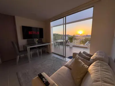 a living room with a couch and a view of the sunset at 2 cuartos terraza piscina AC in Cartagena de Indias