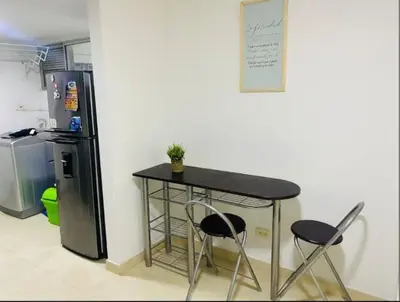 a table and two chairs in a kitchen with a refrigerator at Apartamento en Barranquilla in Barranquilla