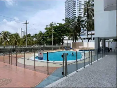 a swimming pool with a fence next to a building at Apt luxury wifi AC pool at Cartagena in Cartagena de Indias