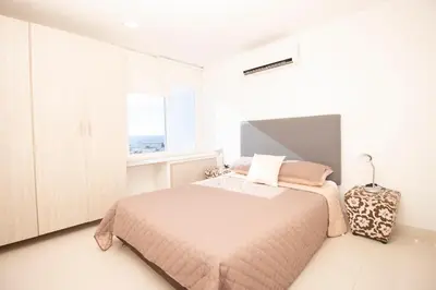 a white bedroom with a bed and a window at Riviera Beach - Apartamento con vista al mar in Cartagena de Indias