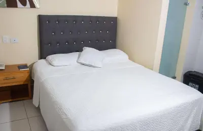 a bedroom with a white bed with a black headboard at Hotel Catedral inn B SAS in Barranquilla