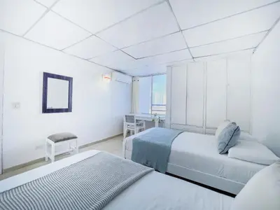 a white room with two beds and a desk at Riviera Summer - Apartamento con balcón in Cartagena de Indias