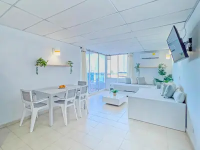 a white living room with a table and a couch at Riviera Summer - Apartamento con balcón in Cartagena de Indias