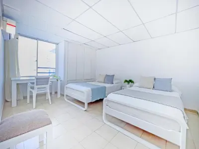 a white room with two beds and a table at Riviera Summer - Apartamento con balcón in Cartagena de Indias