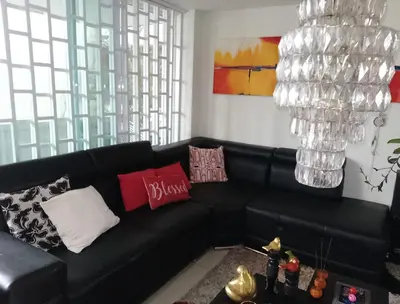 a black leather couch in a living room with a chandelier at Apartamento de lujo alto prado in Barranquilla