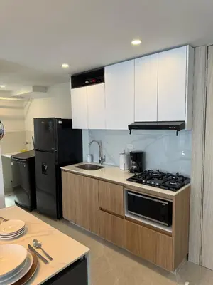 a kitchen with white cabinets and a black refrigerator at Luxury Apartments in Barranquilla