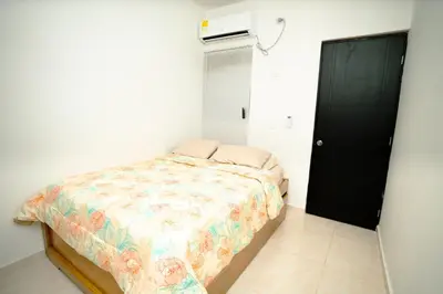 a small bedroom with a bed and a black door at Casa Murillo Toro in Cartagena de Indias
