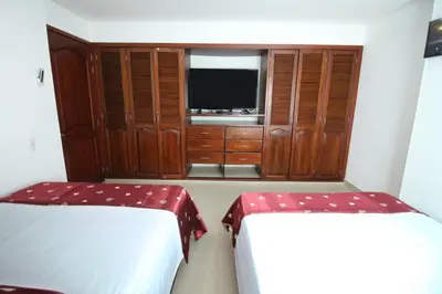 a bedroom with two beds and a tv and wooden cabinets at Alojamiento en Torres del Lago in Cartagena de Indias