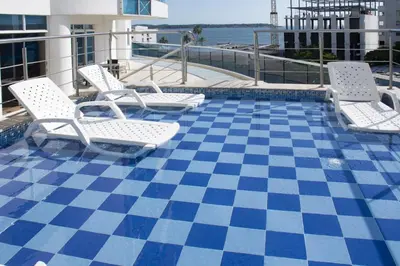 a pool with white chairs and a checkerboard floor at Alojamiento en Torres del Lago in Cartagena de Indias