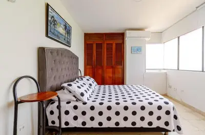 a bedroom with a black and white bed and a chair at Hermoso Apto Frente Al Mar in Cartagena de Indias
