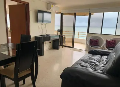 a living room with a couch and a table with a television at Hermoso Apto Frente Al Mar in Cartagena de Indias