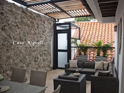 a patio with couches and chairs and a stone wall at Casa Migueli, exclusiva casa con jacuzzi en terraza in Cartagena de Indias