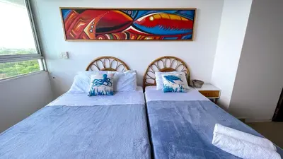 two beds in a room with a painting on the wall at Magico Apartamento Frente al Mar 3 Habitaciones MSC64 in Coveñas