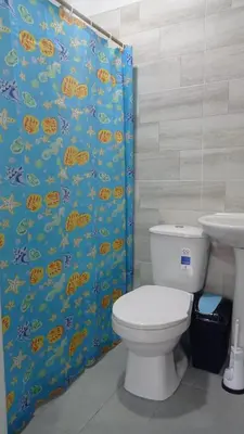 a bathroom with a toilet and a shower curtain at Hostal berpé in Coveñas