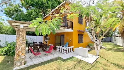 a yellow house with red chairs and a table at Casa Guadalupe Coveñas in Coveñas