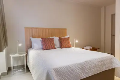a bedroom with a large white bed with colorful pillows at New Pueblito Suites - Cerca a la Playa in Cartagena de Indias