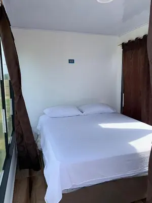 a white bed in a room with a window at Hostal pura vida in San Bernardo del Viento