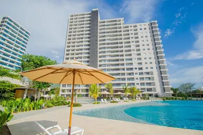 a hotel with an umbrella and a pool and a building at Exclusiva Suite Frente al Mar in Santa Marta