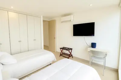 a bedroom with two beds and a tv and a desk at Extraordinario!! Salida Directa Playa Sonesta Cartagena Morros in Cartagena de Indias