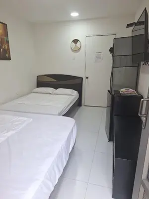a hotel room with two beds and a door at Amplia habitación independiente a 2 cuadras de la playa y el aeropuerto in Cartagena de Indias