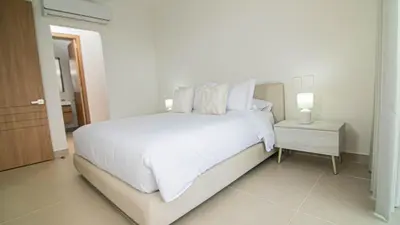 a white bedroom with a large bed and a nightstand at New And Luxury Apartment 3BR In Baia Kristal in Los Arrayanes