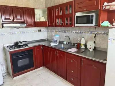 a kitchen with red cabinets and a stove and microwave at Apartamento Villa Saika in Coveñas