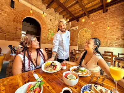 two women and a man sitting at a table eating food at Masaya Cartagena in Cartagena de Indias