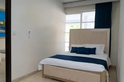 a bedroom with a bed with blue pillows and a window at Villa exclusiva junto al mar en Cartagena in Cartagena de Indias