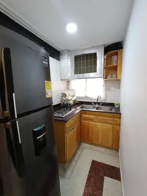 a kitchen with a black refrigerator and wooden cabinets at Acogedor Apartaestudio Laguito 1 Habitacion N4A2 in Cartagena de Indias