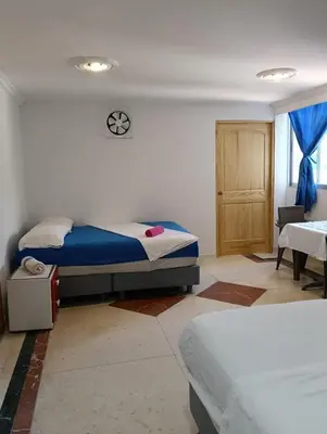 a bedroom with two beds and a table and a chair at Acogedor Apartaestudio Laguito 1 Habitacion N4A2 in Cartagena de Indias