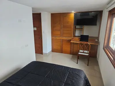 a bedroom with a bed and a desk with a television at Migo in Cartagena de Indias