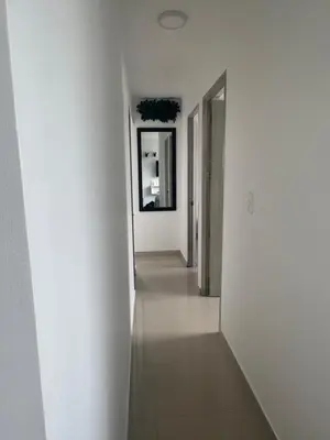 a hallway with white walls and a long hallway with a mirror at nice and affordable in Cartagena de Indias