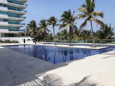 a swimming pool with palm trees and a building at Stunning 2BD Apartment Pool - Oceanview Cartagena in Cartagena de Indias