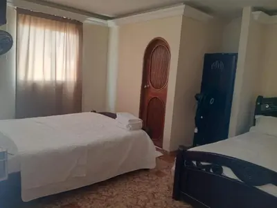 a bedroom with two beds and a wooden cabinet at Hotel San Francisco Inn in Barranquilla