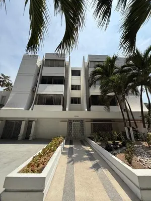 a large white building with palm trees in front of it at Barrio El Golf Apartment in Barranquilla