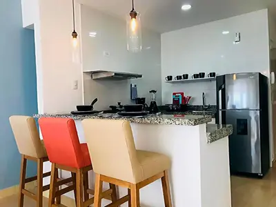 a kitchen with a counter with chairs and a refrigerator at Vive 801 in Cartagena de Indias