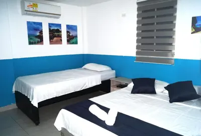 two beds in a room with blue walls at Dilla House in Cartagena de Indias