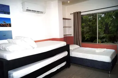 two beds in a room with a window at Dilla House in Cartagena de Indias