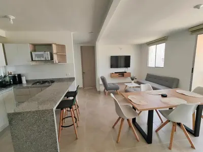 a kitchen and living room with a wooden table and chairs at Encantador Apartamento en Serena del Mar in Manzanillo del Mar