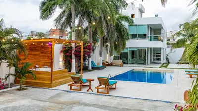 a house with a swimming pool and palm trees at Casa Romero Cartagena Casa de Playa in Cartagena de Indias